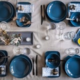 Mahaia, FÄRGKLAR plater urdinekin, mahai-tresnak beltzak, edalontzi gardenak, kandela txikiak eta lore-apainketarekin.