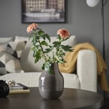 Lore arrosak, katilua, liburuak eta sofa dituen loreontzia.