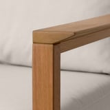 Eukaliptozko egurrezko estruktura trinkoko lehen planoa, akabera leuna, kanpoko sofa baten zati bat.