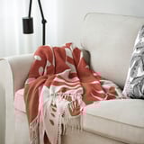 Lore laranja eta zurien manta, sofa beigean lanpararekin.