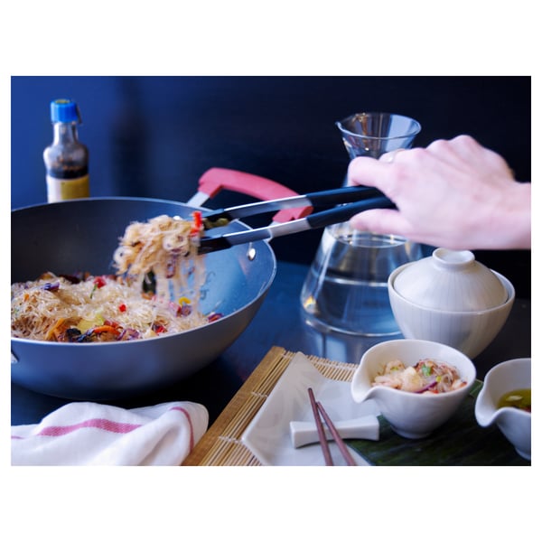 Fideo plater bat ikeazko heldutasun pintzarekin zerbitzatzen duen pertsona, wok baten antzeko zartagin baten janaria hartzeko erabiltzen dituena.