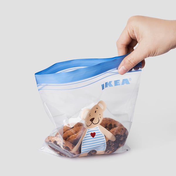 IKEA ISTADen poltsa errebelagarri bati eusten dion esku bat, pelutxe eta gaileta animalia bat duena.