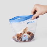 IKEA ISTADen poltsa errebelagarri bati eusten dion esku bat, pelutxe eta gaileta animalia bat duena.