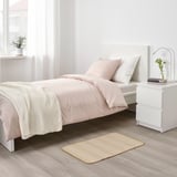 Logela minimalista, jute beige alfonbra eta banakako bi ohe, dekorazio neutroa, landarea eta liburuak.