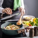 Pertsonak zartaginaren estalkia altxatzen du, eta arroz egosi plater bat erakusten du zartagin gris turkesa batean, egurrezko kirtenarekin berogailu batean. Inguruan, katilu eta belar batzuk daude.