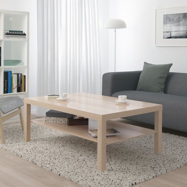 Areto modernoa, LACK zentroko mahaia, sofa grisa, alfonbra, apalategia eta zutik dagoen lanpara dituena.