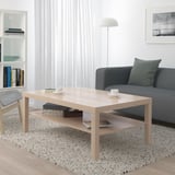 Areto modernoa, LACK zentroko mahaia, sofa grisa, alfonbra, apalategia eta zutik dagoen lanpara dituena.
