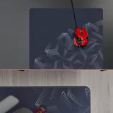Joko iluneko idazmahaia, sagu ilunezko alfombrillarekin, patroi geometriko batekin. Kable batekin jolasteko mouse gorri bat, erabiltzeko prest dagoen kokoskoan.