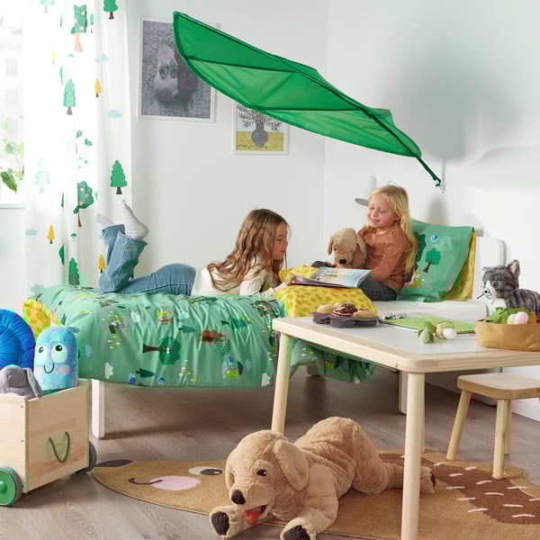 Umeentzako gela, ohea errezela berdearekin, bi neskato jolasean, pelutxezko animaliak eta jostailuak.