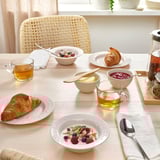 Egurrezko mahaia, beirate, yogurta, fruitu gorriak, granola, kruasanak eta tearekin. Zumezko aulkia atzealdean.