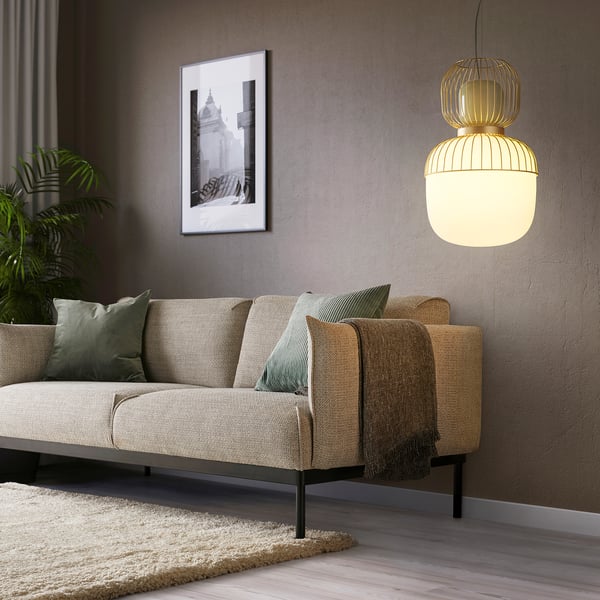 PILBLIXT lanpara zintzilikaridun areto modernoa, sofa beige eta kuxin berdeen gainean.