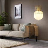 PILBLIXT lanpara zintzilikaridun areto modernoa, sofa beige eta kuxin berdeen gainean.