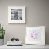 Hondartzan marko zuria duten bi haur zuri-beltz, mahai gainean zintzilik daude, inpresio artistikoak, liburuak, jostailuak eta landareak dituela.