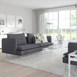 Sofa SÖDERHAMN, erdiko mahaia eta landaretza erakusten duten leihoak dituen egongela modernoa. Diseinu minimalista.