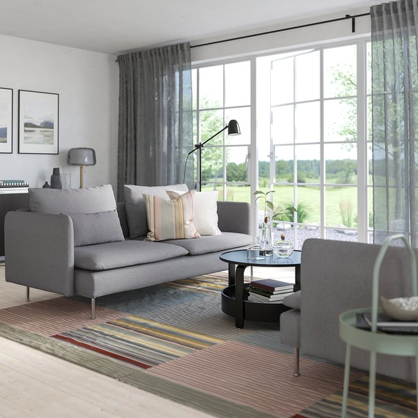 Sofa SÖDERHAMN grisa areto moderno eta minimalistan, leiho handiekin.
