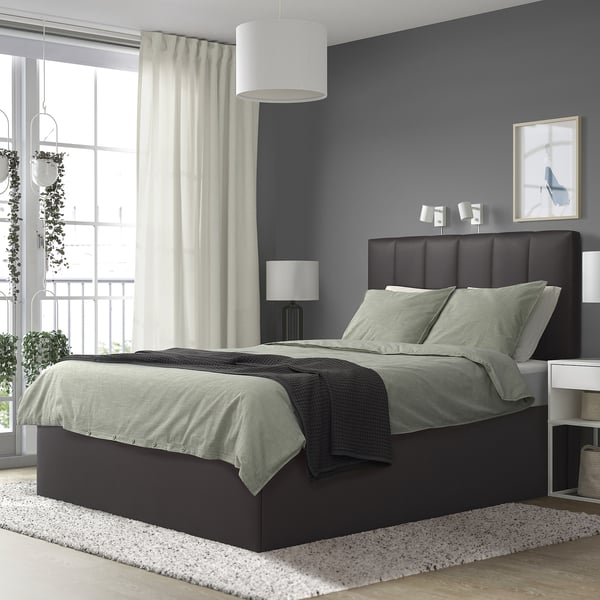 Cama TJßLLE modernoa, gris iluna, izara berdeekin, handia horma urdinaren kontra. Buruko akoltxatua eta gaueko lanparak ditu. Alfonbra eta balkoi ikusiak.