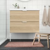 Bainu modernoa haritzezko apaingailuarekin, beirazko dutxarekin eta TOFTBO beige bainu-alfonbrarekin.