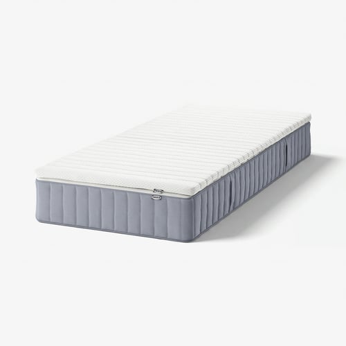 Irudiak IKEA VALEVÅG koltxoi zuri bat erakusten du. Laukizuzen forma, alboko diseinua quiltatua.