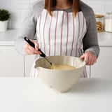 Pertsona batek, masa, VISPNING inklinatu eta ergonomiko nahasketako katilu batean eta erre-moko batekin nahasten du sukalde argitsu batean.