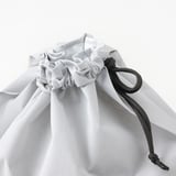 Primeiro plano de bolsa de reciclaxe branca e resistente con cordón negro, deseñada para a clasificación de residuos secos.