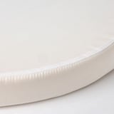Primeiro plano dun colchón suave, branco e redondo con tecido liso e costuras limpas.