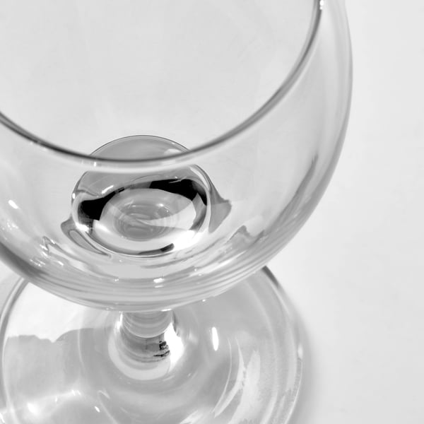 Primeiro plano en branco e negro dun vaso de viño claro e elegante cun talo longo e unha base redonda, mostrando o seu deseño de alta calidade e transparencia.