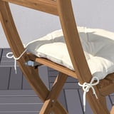 Unha cadeira plegable de madeira cun coxín removible e reversible. Ideal para espazos exteriores como balcóns.
