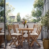 Balcón acolledor con mesa de madeira, cadeiras e luces de corda para comer ao aire libre.