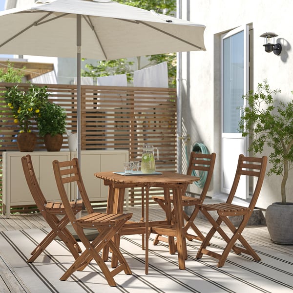 Conxunto de comedor ao aire libre de madeira de acacia marrón ASKHOLMEN con 4 cadeiras plegables e mesa, perfecto para espazos pequenos.
