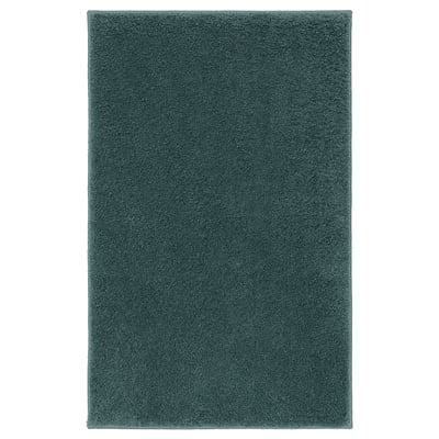 Unha alfombra de baño verde BACKMÅRA, rectangular, suave e peluche, deseñada para o confort e a seguridade con respaldo de látex.