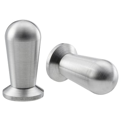 Dous botóns BAGGANÄS de aceiro inoxidable; un redondo cunha base plana, o outro cilíndrico cun acabado suave. Deseño moderno e minimalista.