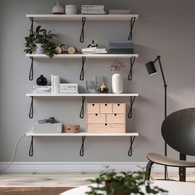 Estante minimalista con estantes brancos BERGSHULT, libros, vasos, plantas, lámpada e cadeira.