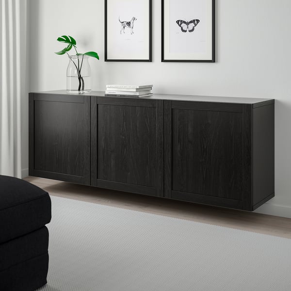 Sala de estar moderna con almacenamento BESTÅ en negro-marrón, liñas limpas, estantes axustables, plantas, libros e arte de parede.
