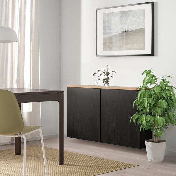 Sala de estar moderna con unidade ikea BESTÅ negra, planta, chan de madeira clara, luz natural.