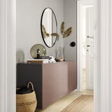 Entrada moderna e minimalista con sideboard rosa claro BESTÅ, espello redondo, lámpada, libros, vaso con flores secas e cesta de vimbio.