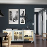 Comedor moderno con paredes azuis escuros, mesa de madeira e taboleiro branco con pratos e fotos.