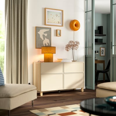 Sala de estar moderna con almacenamento branco BESTÅ , cadeira e mesa. Decorado con vasos e lámpadas para un estilo minimalista.