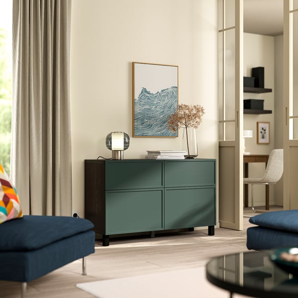 Sideboard verde BESTÅ con 4 compartimentos entre cadeiras de brazos azuis na sala de estar moderna.