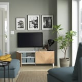 Sala de estar moderna con unidade de televisión BESTÅ, televisión de pantalla plana, cadeiras azuis e decoración.