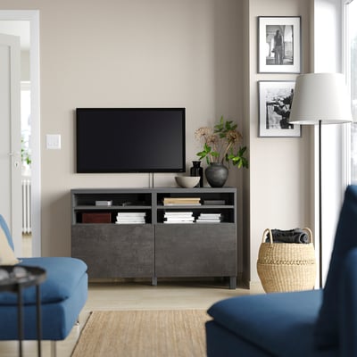 Sala de estar con entretemento descentralizado moderno, con soporte de televisión BESTÅ negro, pantalla plana, sofá azul e decoración.