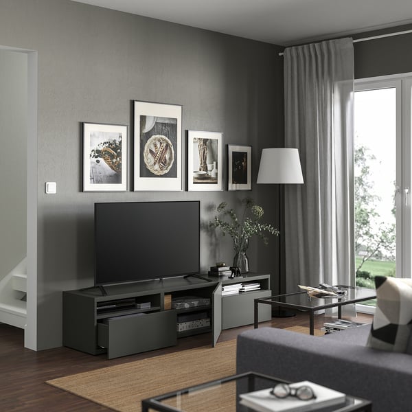 Sala de estar moderna con banco de televisión gris BESTÅ, televisión negra, arte enmarcada, lámpada alta e mesa de café de vidro.