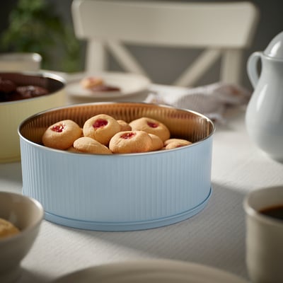 Lata azul BETTHAJ con galletas de marmelada sobre pano de mesa.