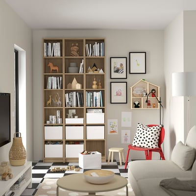 Libraría e área de xogos para adultos e nenos. Estantes de madeira con accesorios en branco e negro. Cadeira vermella para nenos con almofada de puntos.