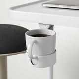 Un soporte branco axustable para portátil sostén unha cunca nun clip, demostrando a súa función de portacopas multitarefa.