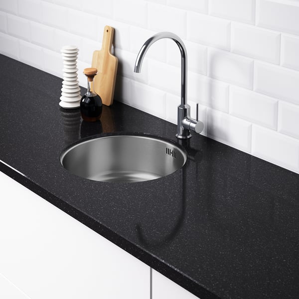 Lavabo de cociña moderno con billa cromada e mesa negra. Lavabo de aceiro inoxidable, sen buratos pre-perforados. Backsplash de azulexos brancos.