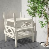O conxunto de mobles brancos para exteriores inclúe unha mesa e dúas cadeiras apilables con deseños xeométricos, perfectas para relaxarse.