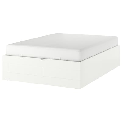 Unha cama branca de BRIMNES con almacenamento inferior. É un deseño moderno con liñas limpas e unha forma rectangular.
