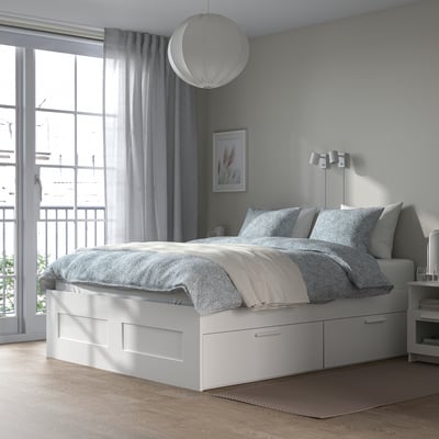Moderna cama branca BRIMNES con caixóns, roupa de cama gris, luz colgante e vista ao balcón. Compacto pero amplo con caixóns grandes.