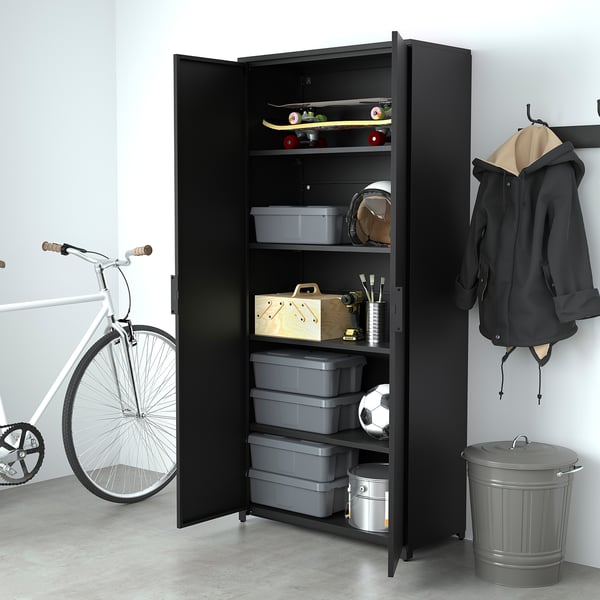 O armario de almacenamento negro no garaxe contén colectores grises, equipos deportivos e ferramentas. Bicicletas e chaquetas nas proximidades.