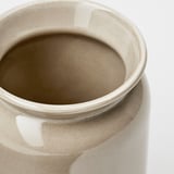 Primeiro plano dun soporte de utensilios de gres. Acabado liso, acristalado, cor neutra. Abertura redonda, os lados curvados cara a dentro.